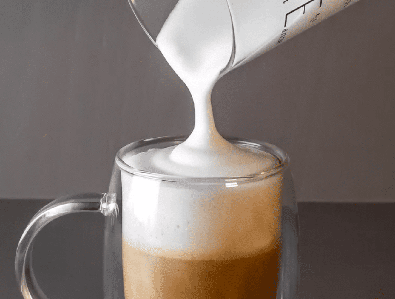 Frothed milk being poured into a mug of coffee