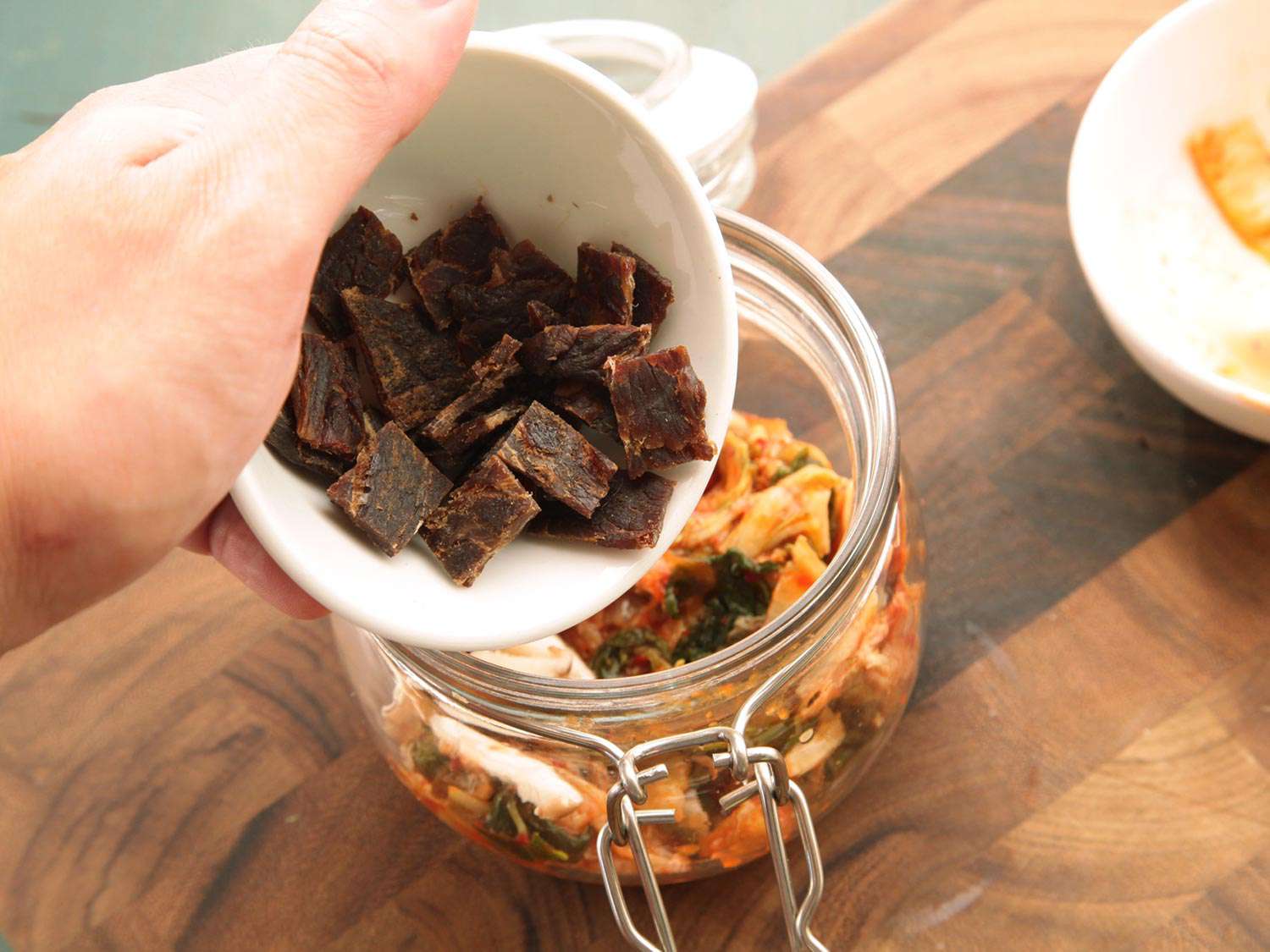 Sliced squares of beef jerky are added to the jar.