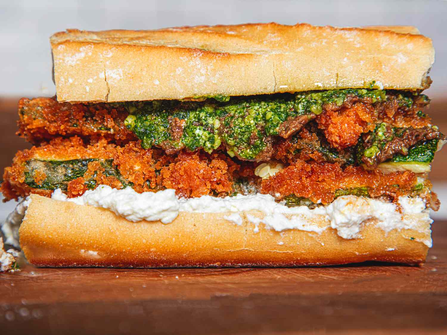 A closeup of a crispy zucchini sandwich with bread ricotta and pesto layers