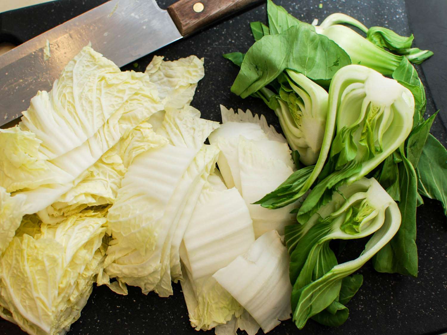 Chopped Napa cabbage and bok choy on a cutting board.
