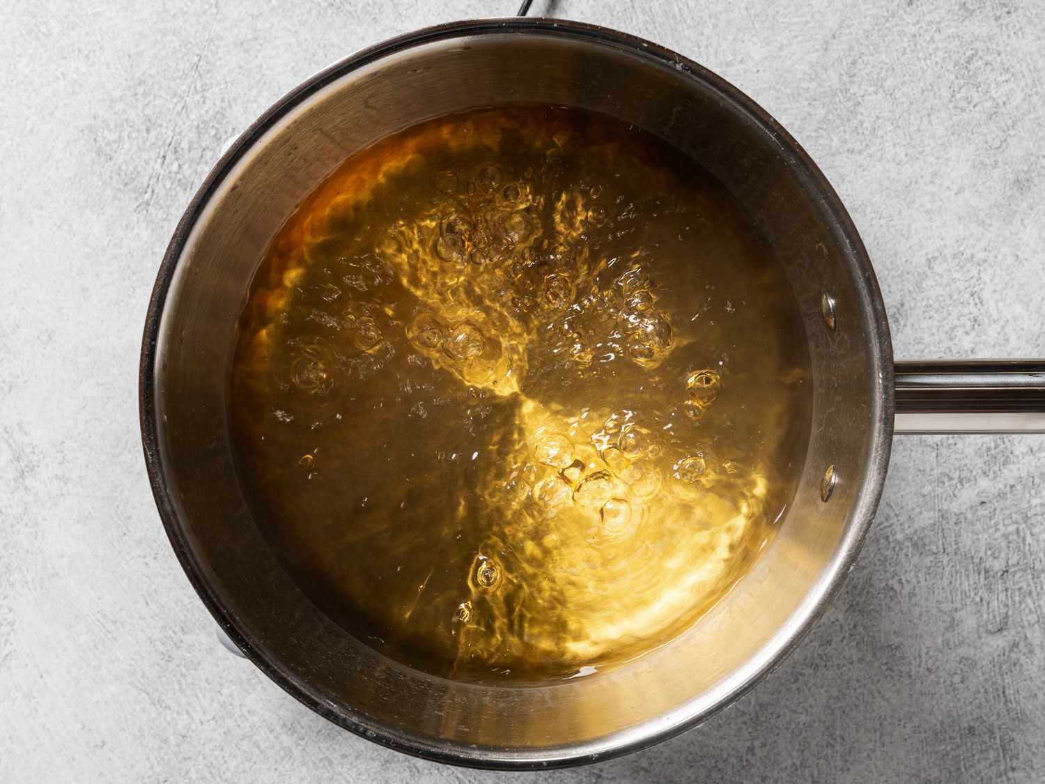 Vinegar, water, and salt coming to a boil inside of a stainless steel saucepan.
