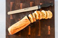 Dexter-Russell Basics 10-Inch Bread Knife With Black Polypropylene Handle next to loaf of bread