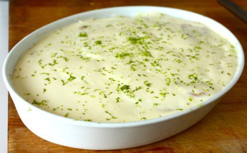 A finished key lime cracker pie in a white serving dish with lime zest sprinkled over the top.