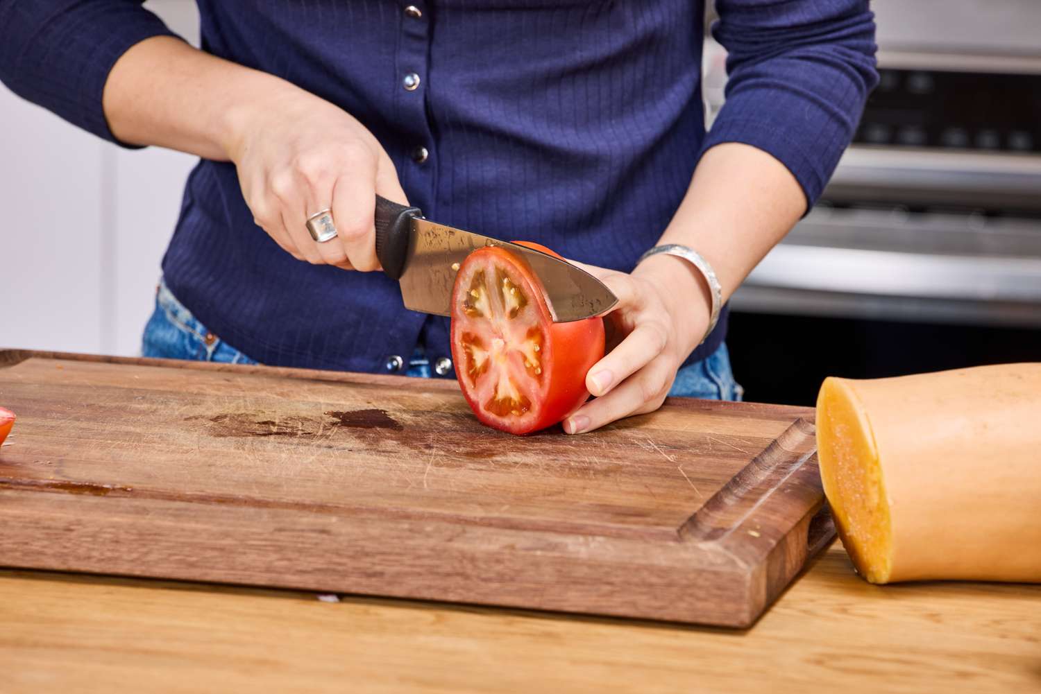 A person slices a tomato using the Mercer Culinary 8-Inch Millennia Chef's Knife