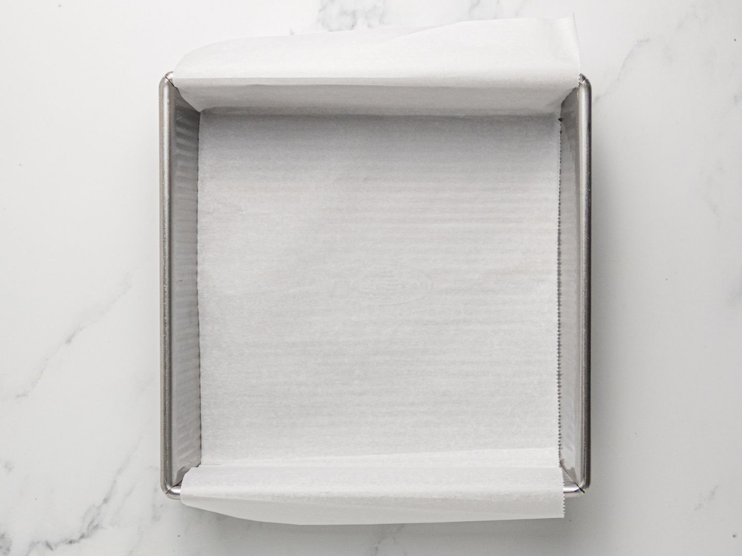 A square baking pan lined with parchment paper