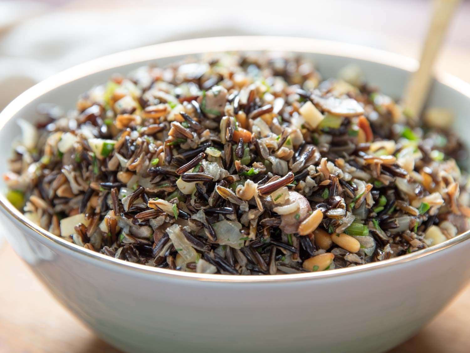 Wild rice salad with mushrooms, celery root, and pine nuts, served in a large white bowl.