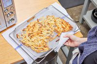 A hand holding a rack of fries that cooked in the Breville the Smart Oven Air Fryer