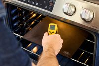 Taking the temperature of a pizza steel in the oven using an infrared thermometer.
