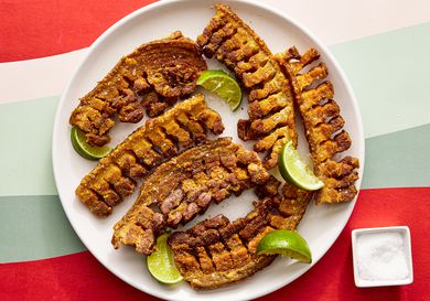Overhead view of chicharrones on a plate with a small bowl of salt off to the side 