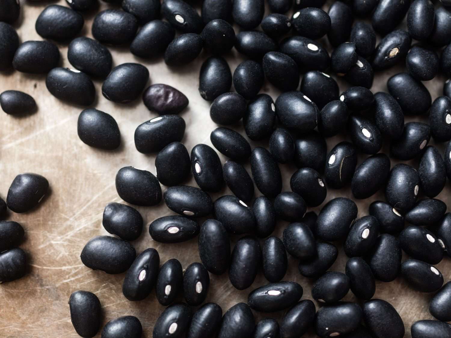Closeup of dried black beans on a cutting board