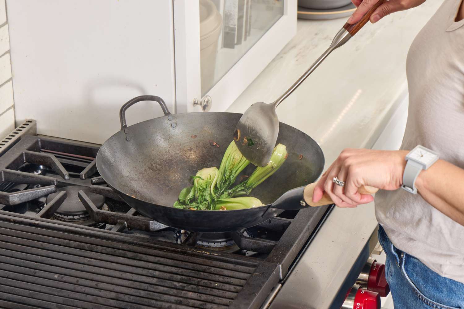 Bok choy being stir fried in the Mammafong Pre-Seasoned Blue Carbon Steel Flat-Bottom Pow Wok