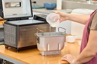 A person adding water to the Zojirushi Home Bakery Virtuoso Plus Bread Maker basket