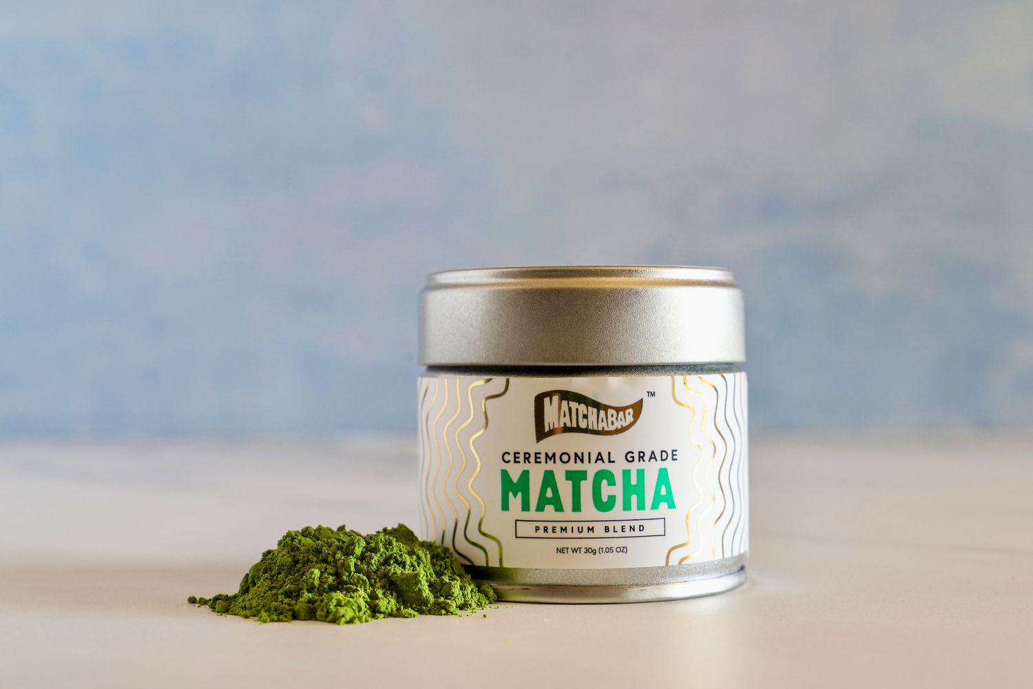 A container of Matcha Bar Premium Blend next to a pile of the powder