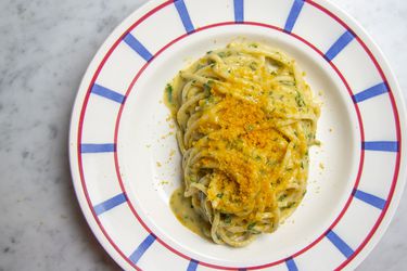 Pasta con la Bottarga resting on a white, red, and blue patterned plate.