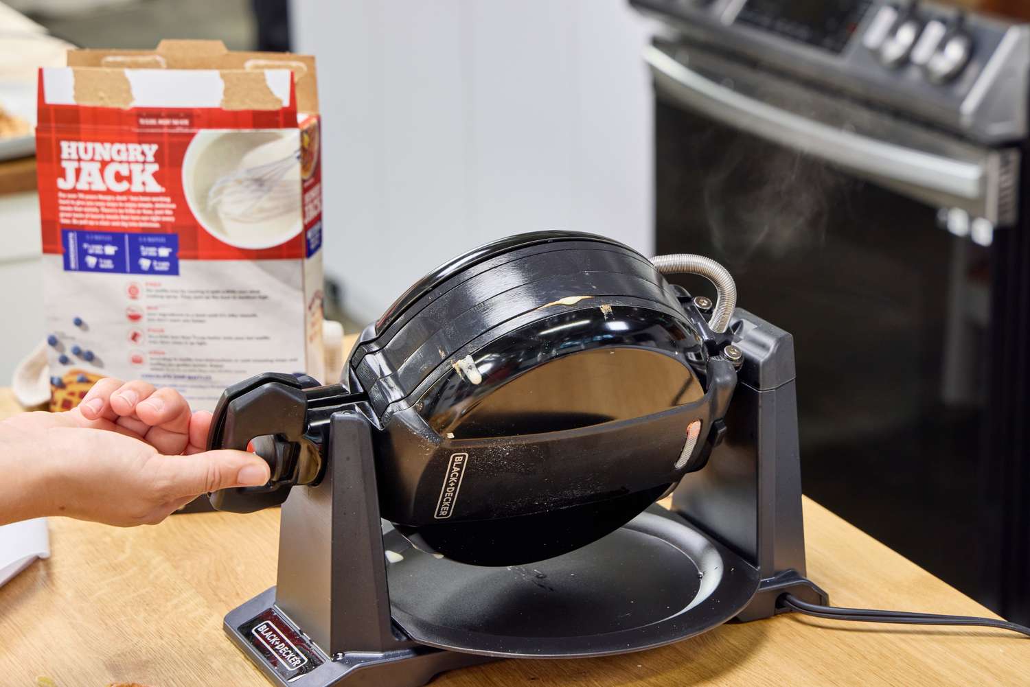 A person turns the Black+Decker Double Flip Rotating Waffle Maker over while cooking