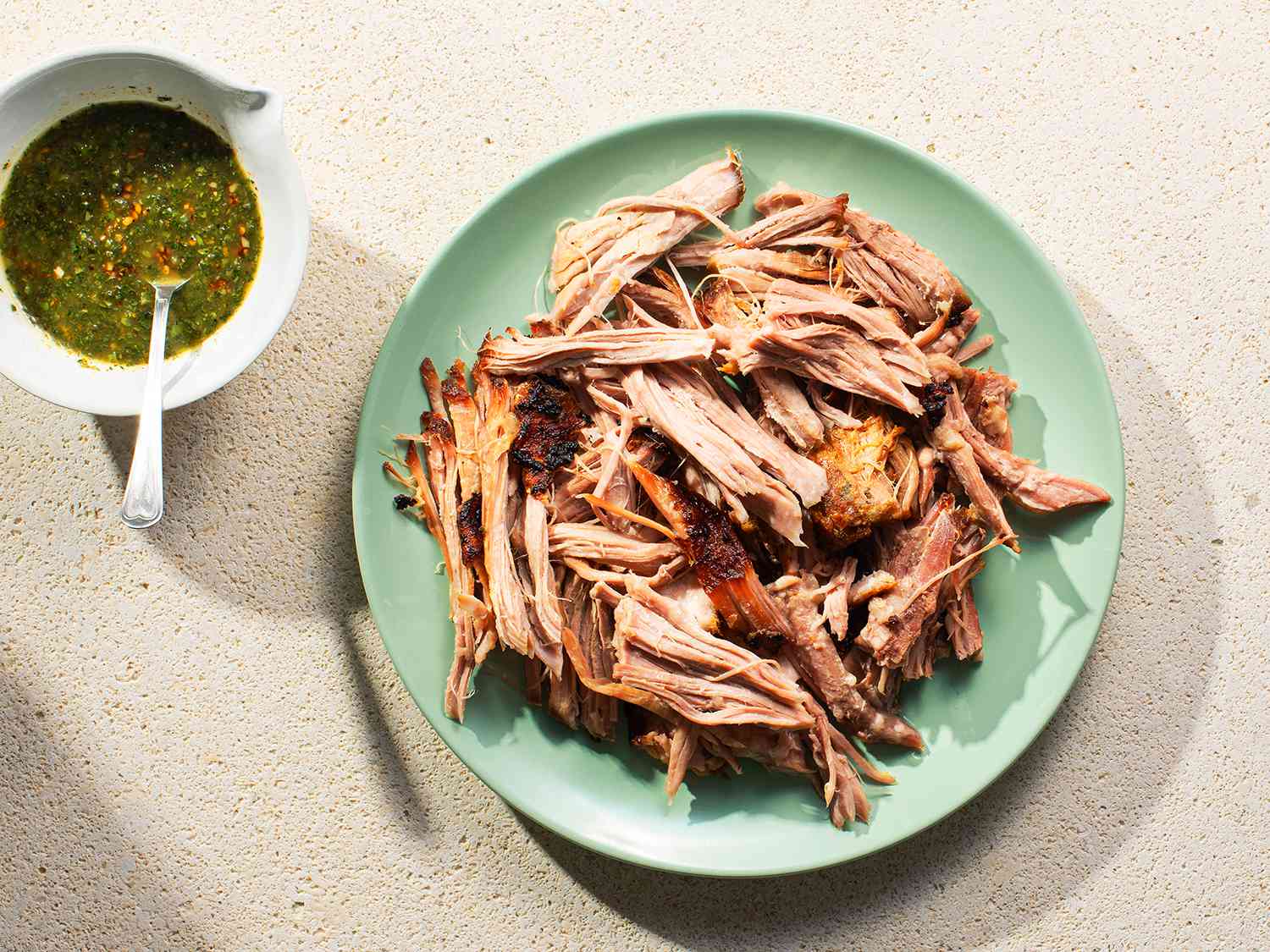 Overhead view of Cuban-Style Roast Pork Shoulder With Mojo, served on a seafoam colored platwe.
