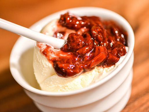A bowl of vanilla ice cream topped with strawberry balsamic sauce.