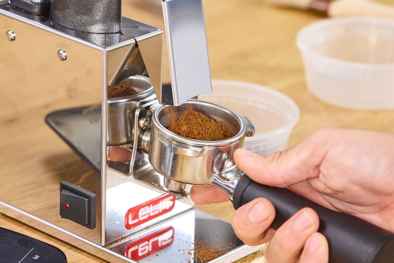 Ground coffee is dispensed into a portafilter from the Lelit Fred Tempo Burr Grinder