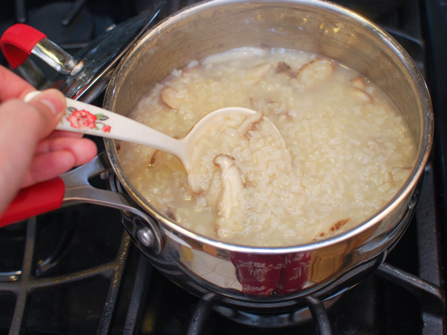 The rice and shiitake slices are stirred in the pan.