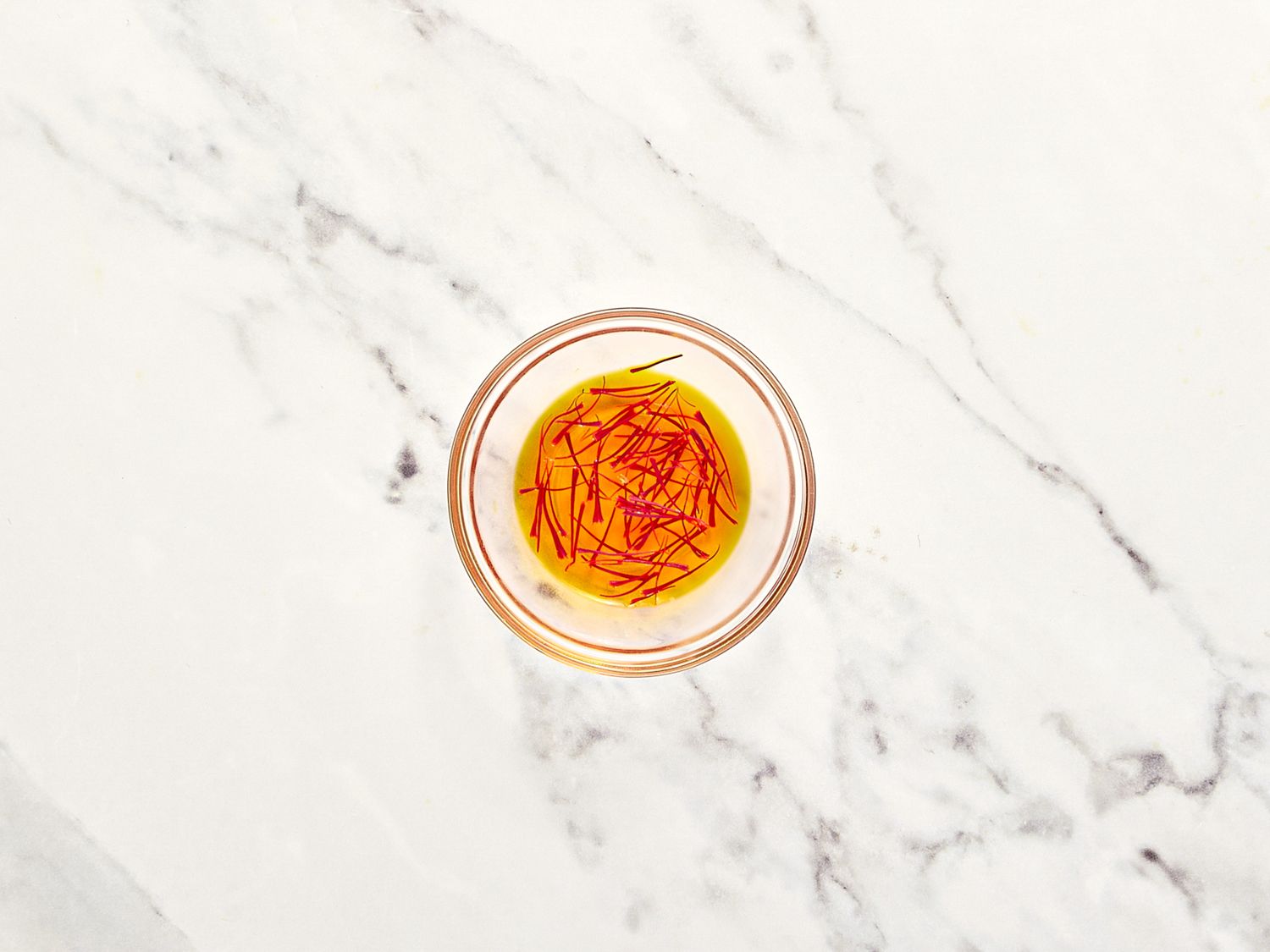 Bowl of saffron threads in liquid on a marble surface