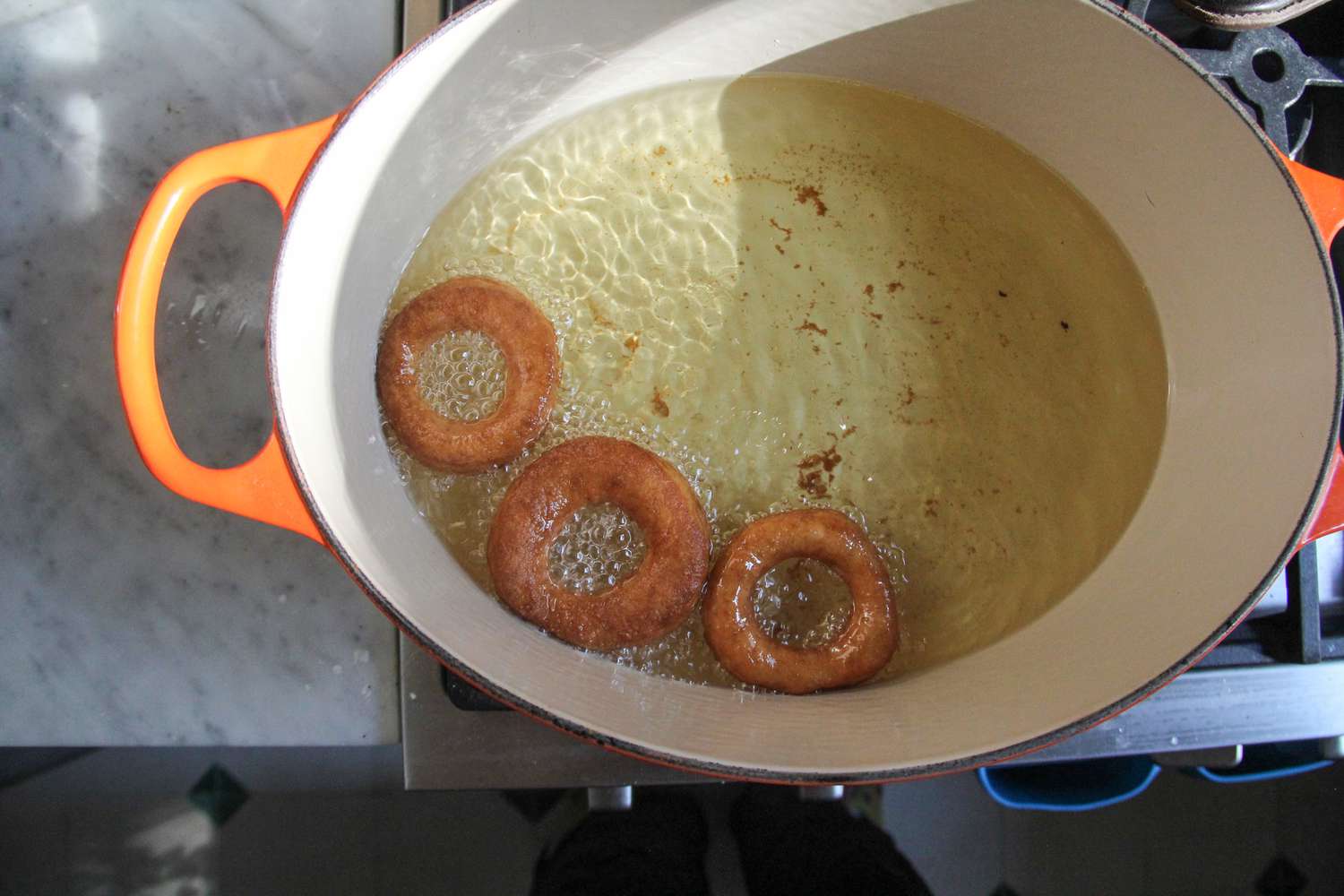 Donuts cooking in oil in a pan.