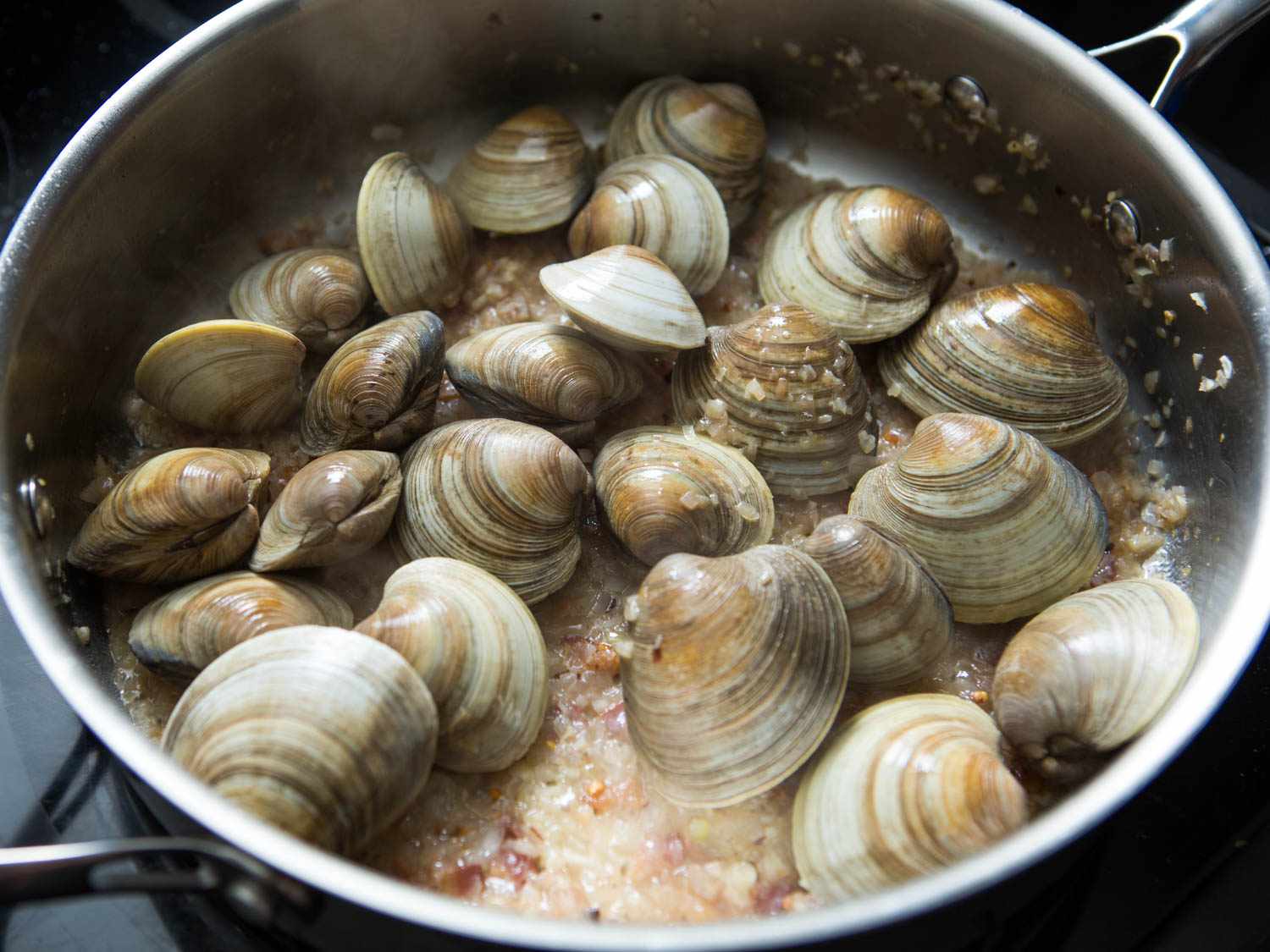 White wine and clams added to the stainless steel pan 