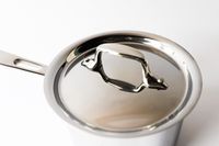 A metal saucepan with a lid and handle on a white background