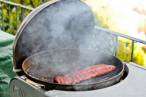 Smoke rising from an outdoor grill with rack of barbecue ribs