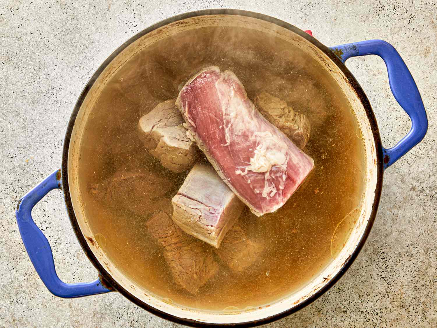 Pot of boiling broth with meat pieces visible