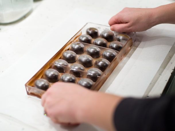Turning the bonbon mold over to a clean surface to release them. 