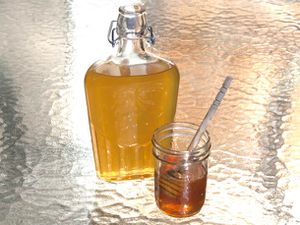 A bottle of honey liqueur next to a jar of honey