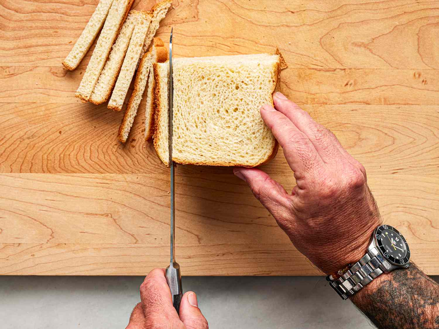Overhead view of cutting the crust off of bread