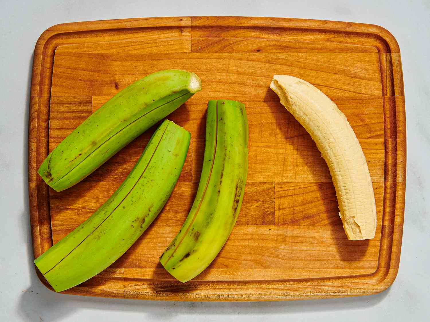Plantains on wooden cutting board with the edges cut off