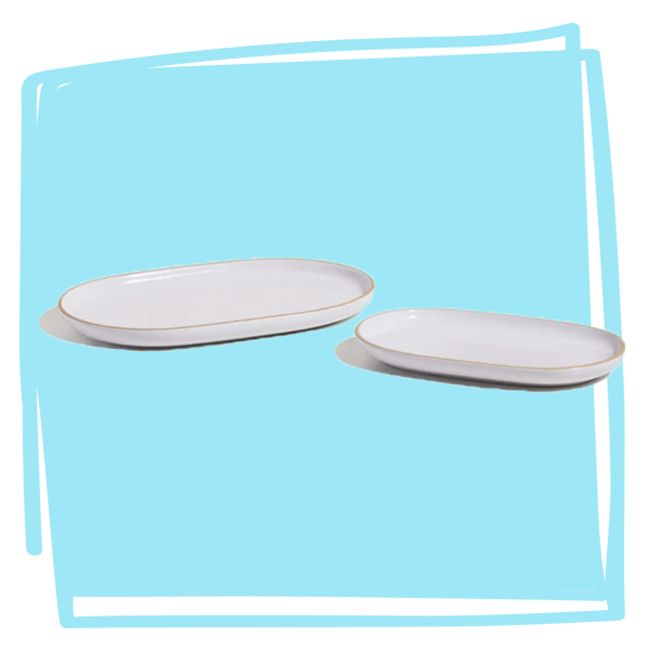 Two oval serving platters arranged on a blue background set at an angle for display