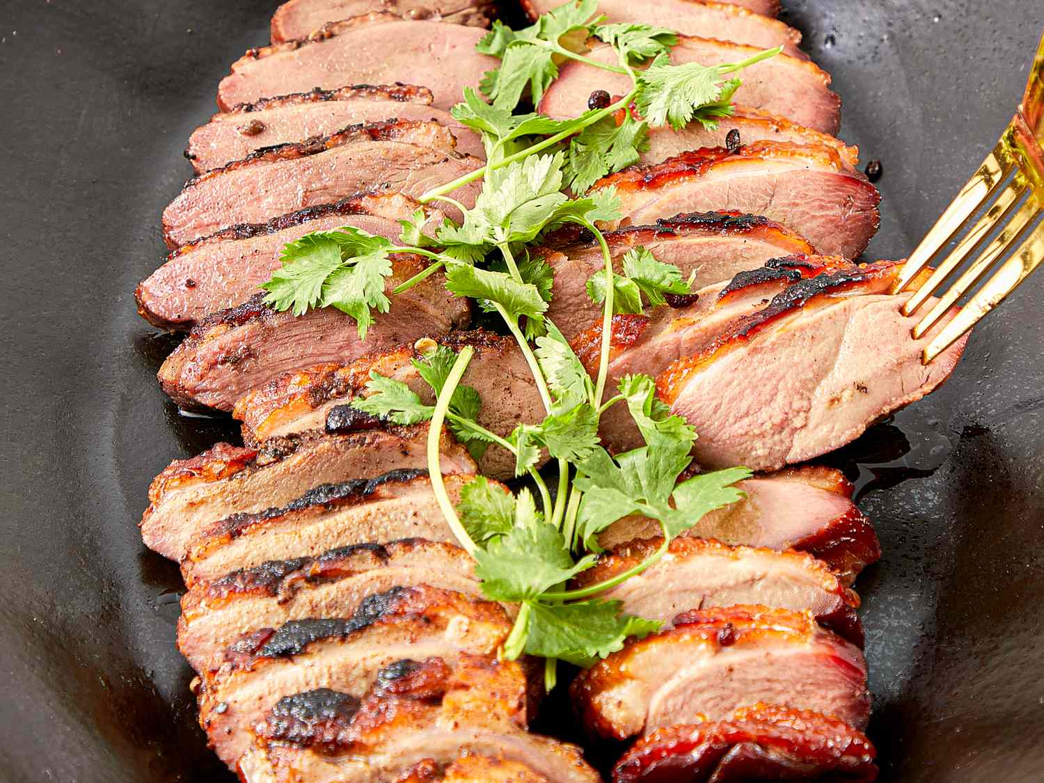 Sliced smoked duck breasts garnished with fresh herbs