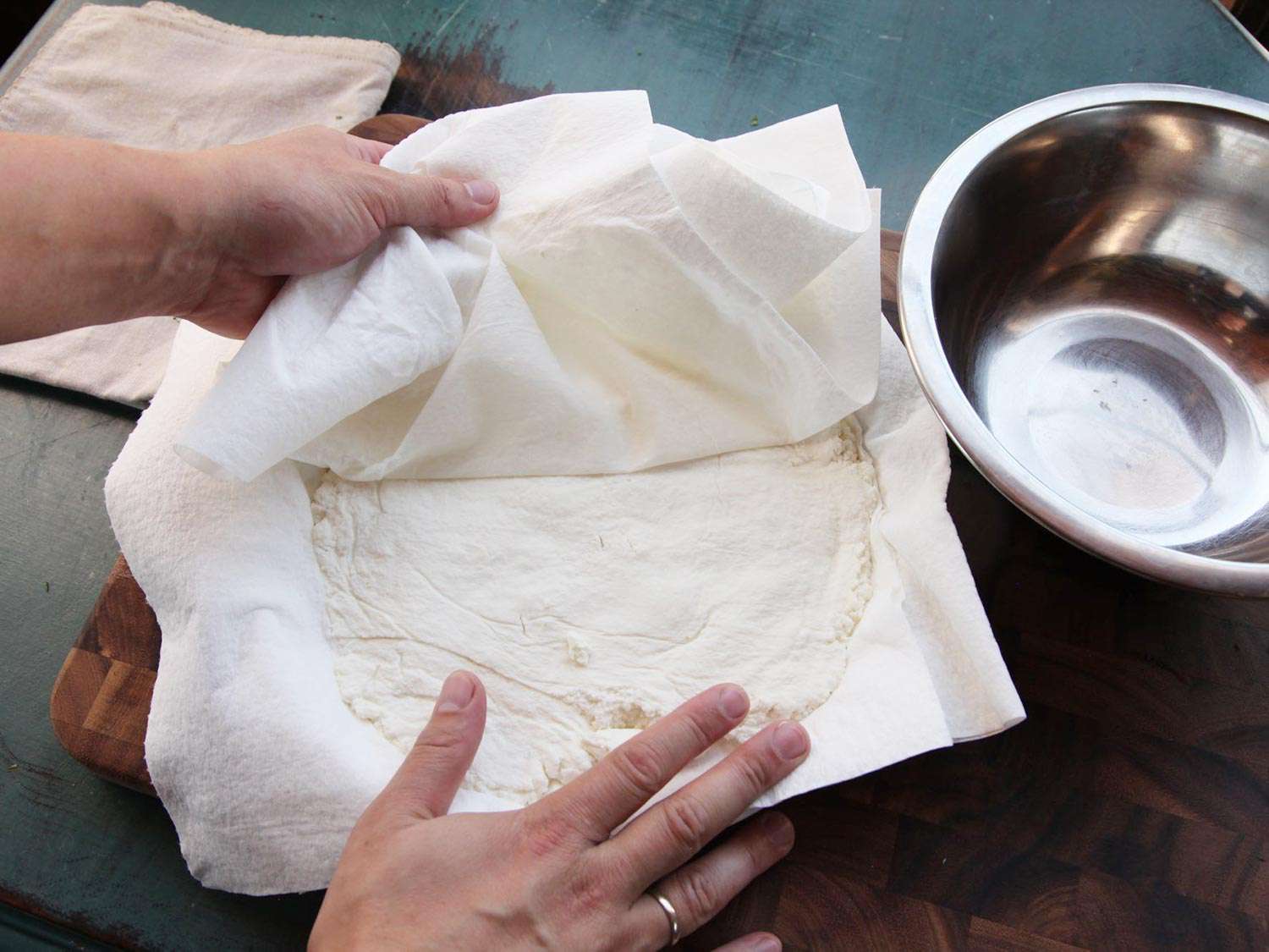 Peeling off paper towel from ricotta to drain of excess moisture. 