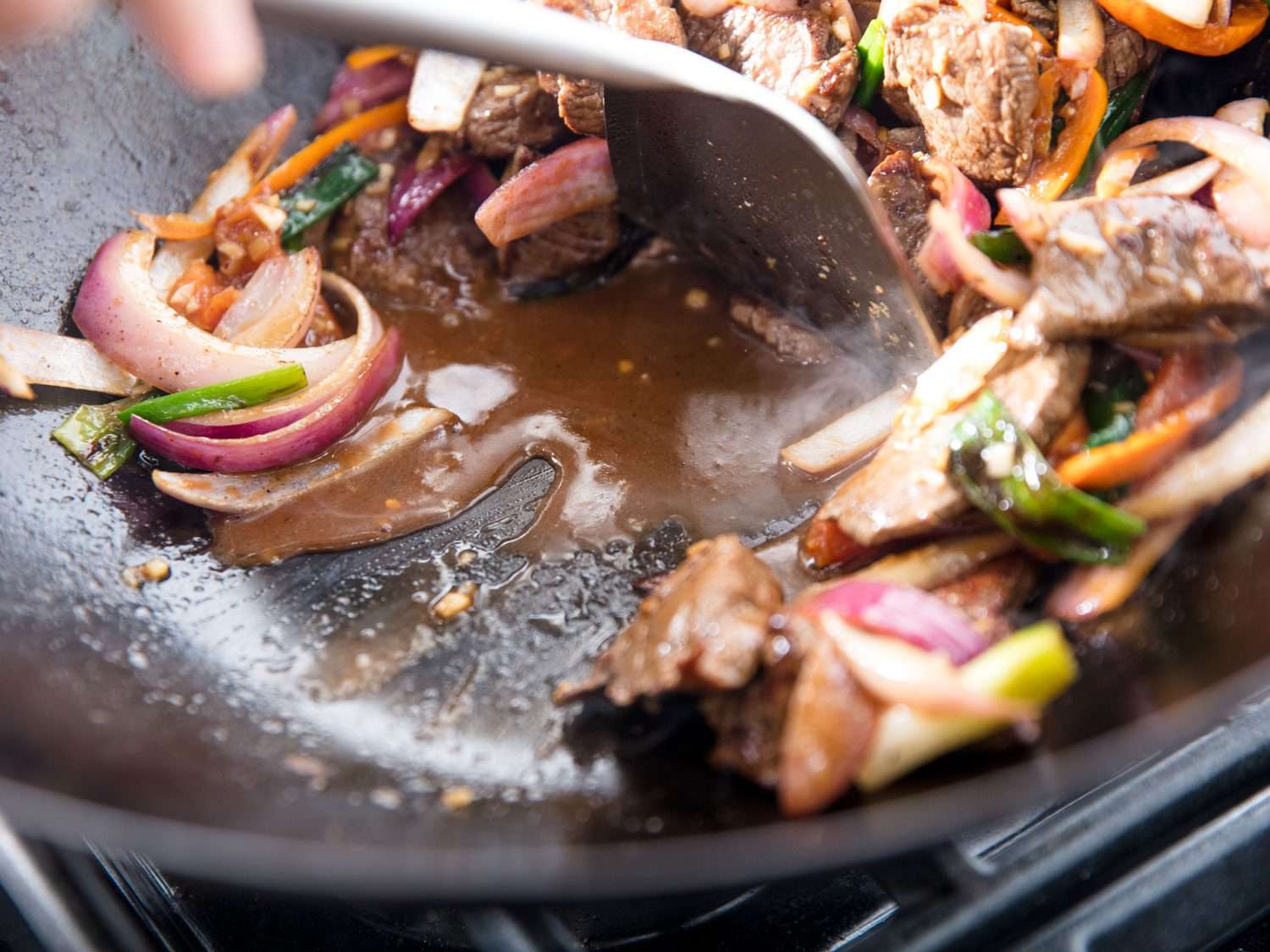 Saucy juices in a wok of Peruvian lomo saltado.