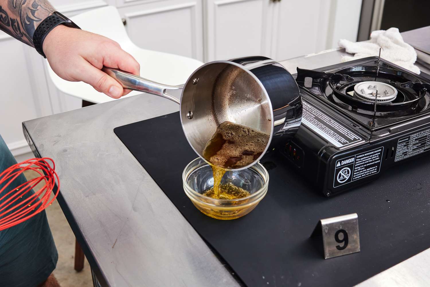 A person pouring brown butter from a saucepan into a bowl
