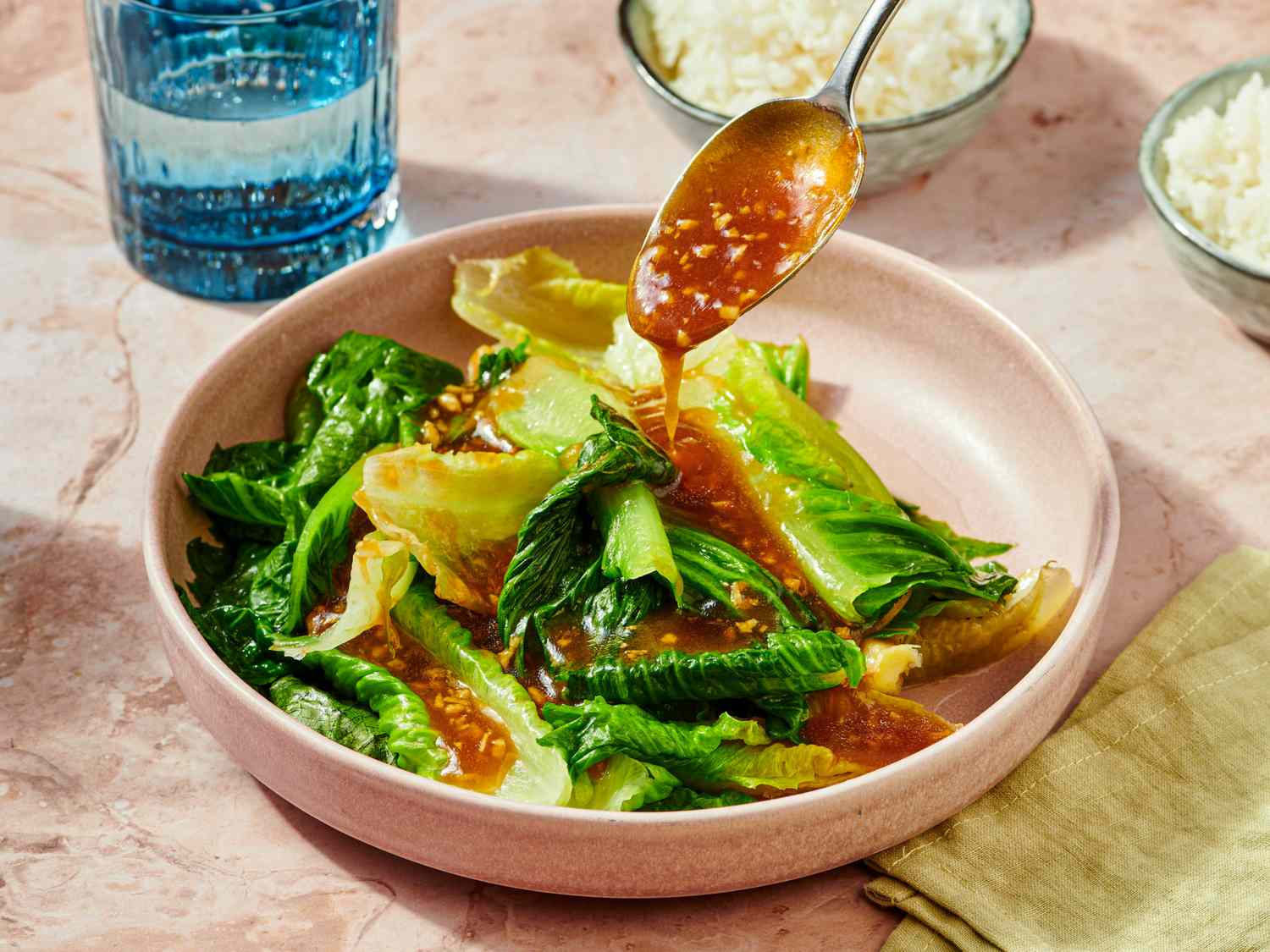 Sauteed lettuce with oyster sauce served in a bowl garnished with sauce from a spoon