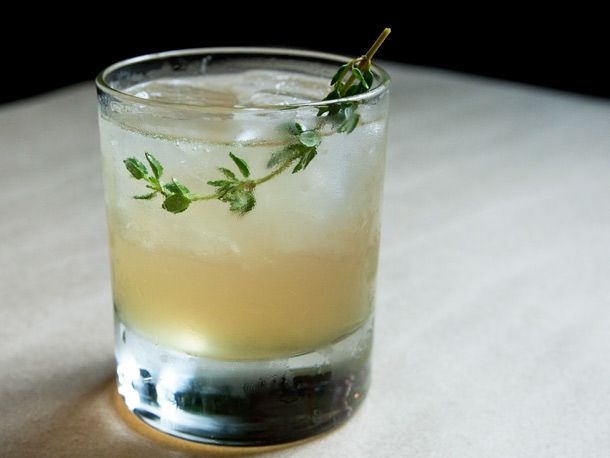A cocktail called the Apricot Rhyme made with apricot-infused rye and thyme simple syrup, garnished with fresh thyme.