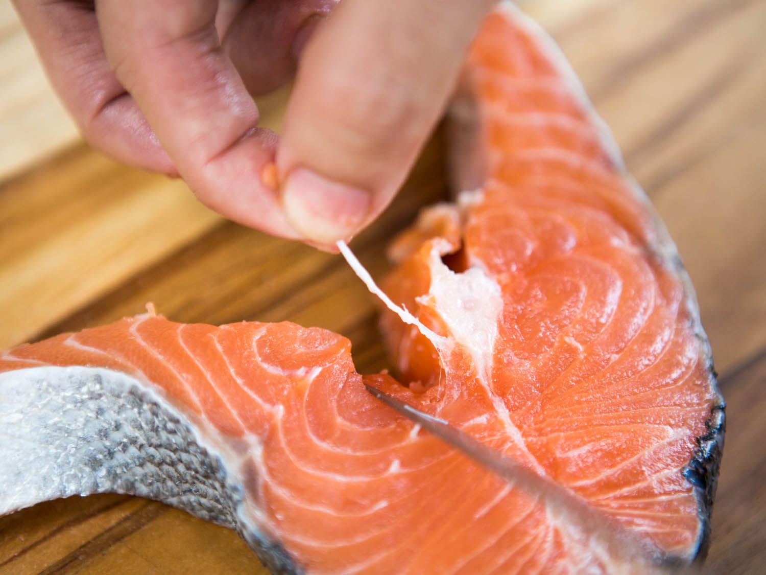 Removing the bone from the center of the salmon steak.