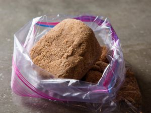 A large, hardened lump of brown sugar in a zip-top bag, the opening of which has been rolled back and propped open.