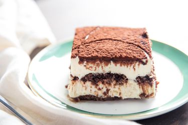 A slice of rich and creamy tiramisu on a dessert plate. 