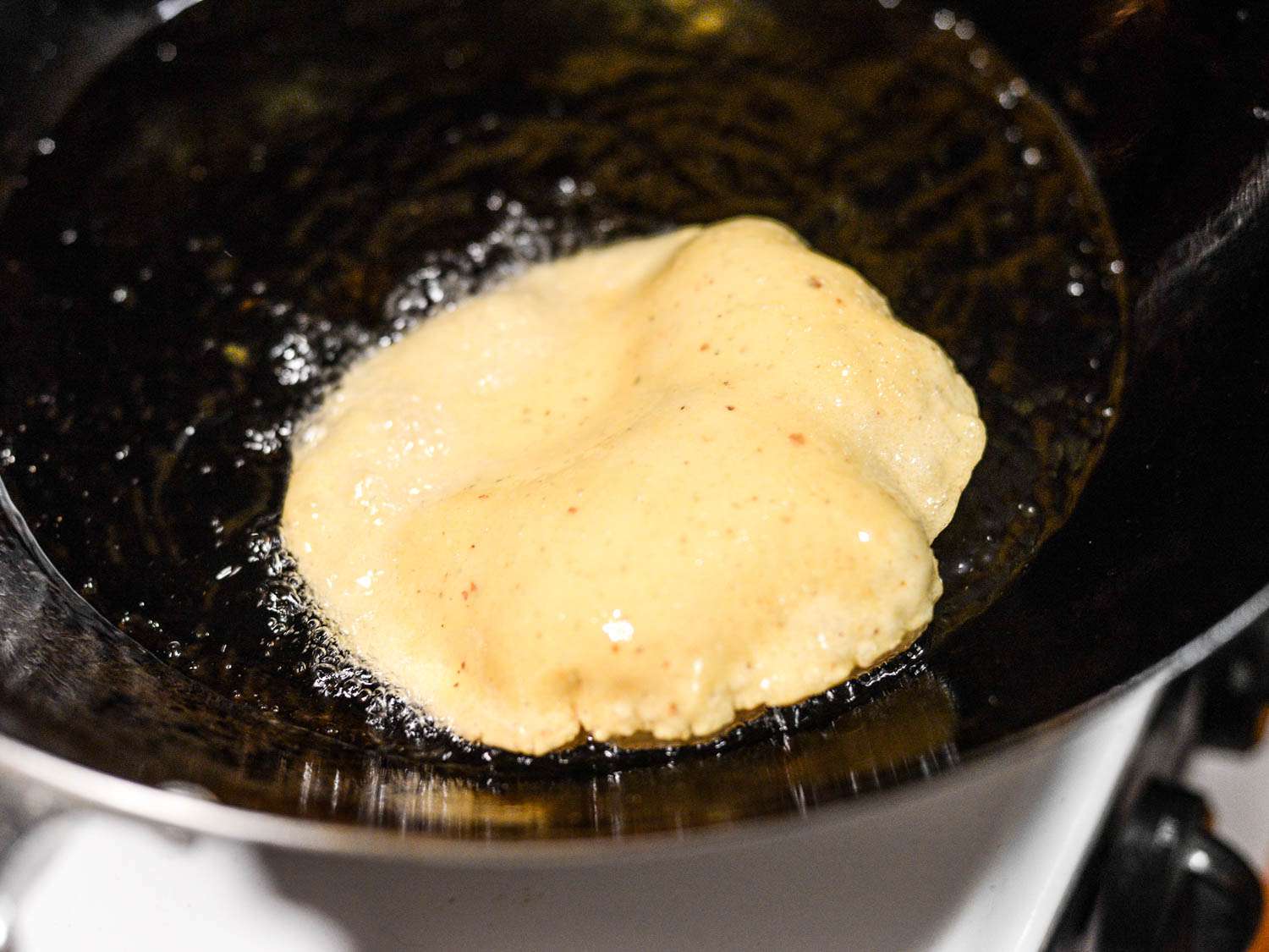 Deep-frying a masa tortilla for puffy San Antonio-style tacos.