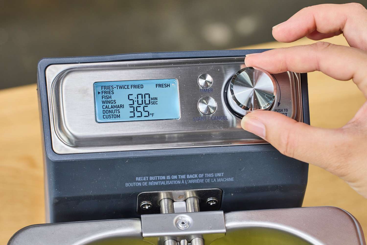 A hand adjusting the control knob on the Breville BDF500XL Smart Fryer