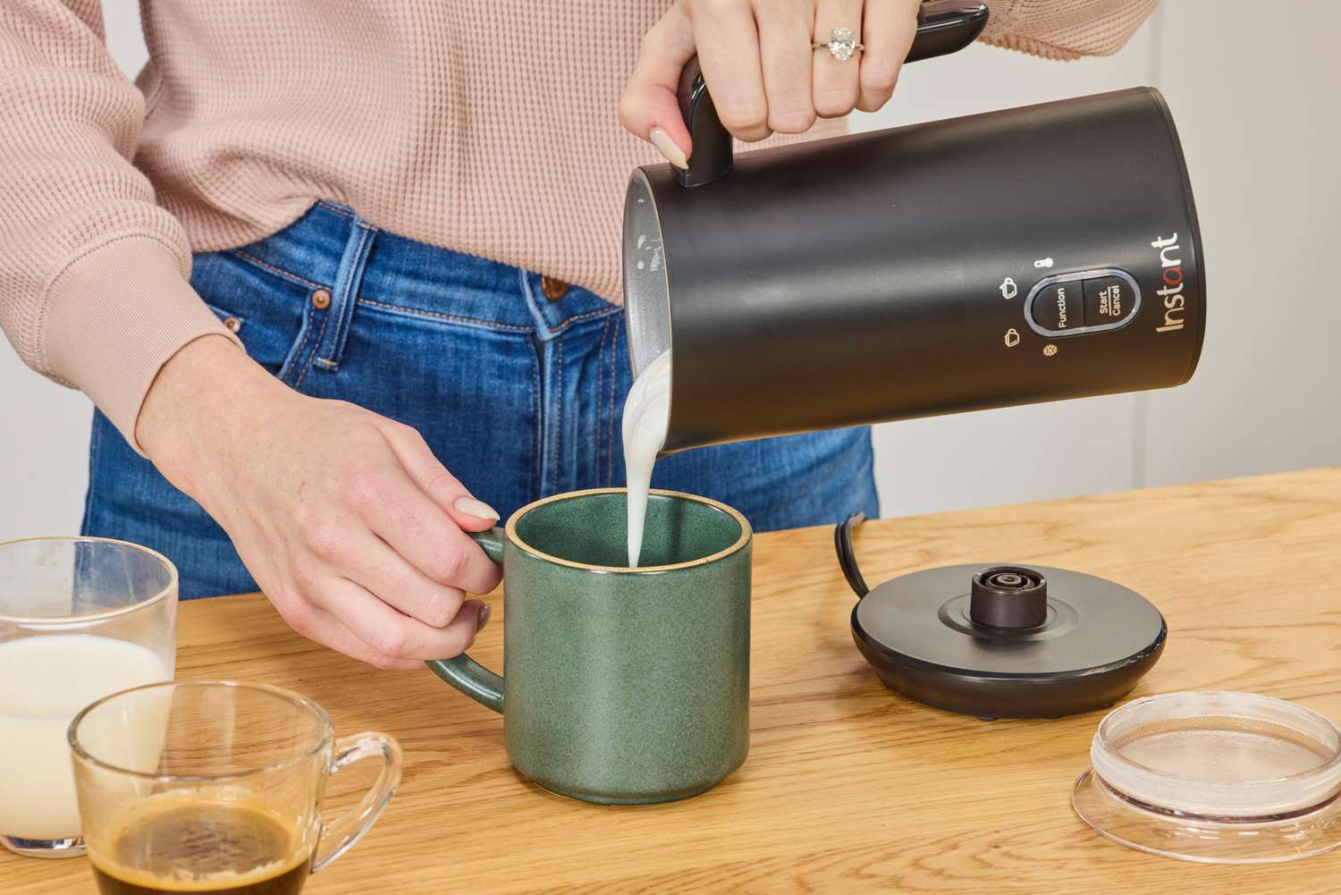 A person pouring from the Instant milk frother into a mug.