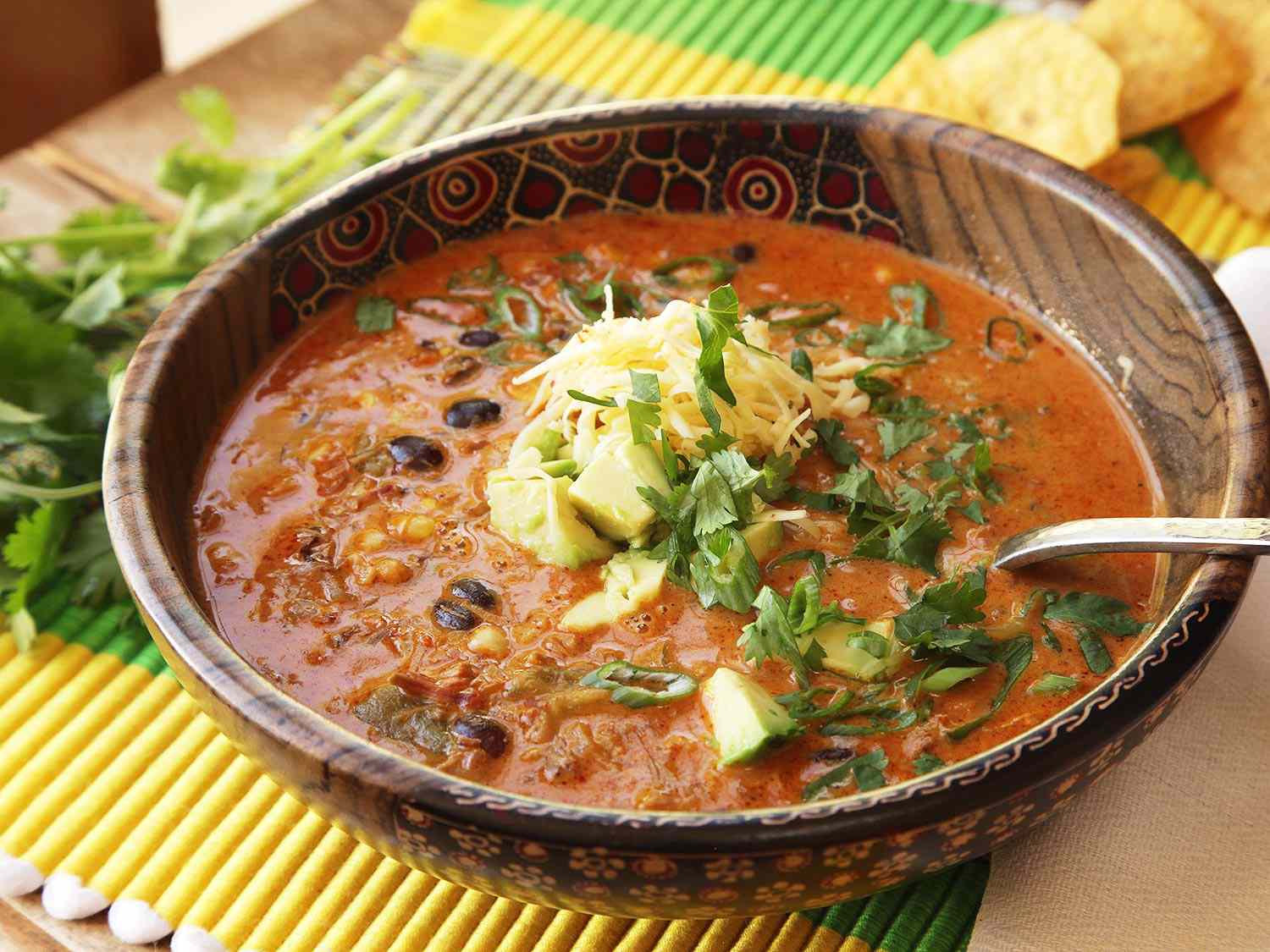 Creamy chicken enchilada soup served in a decorative wooden bowl