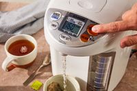 A person dispensing hot water using the Zojirushi hot water dispenser.