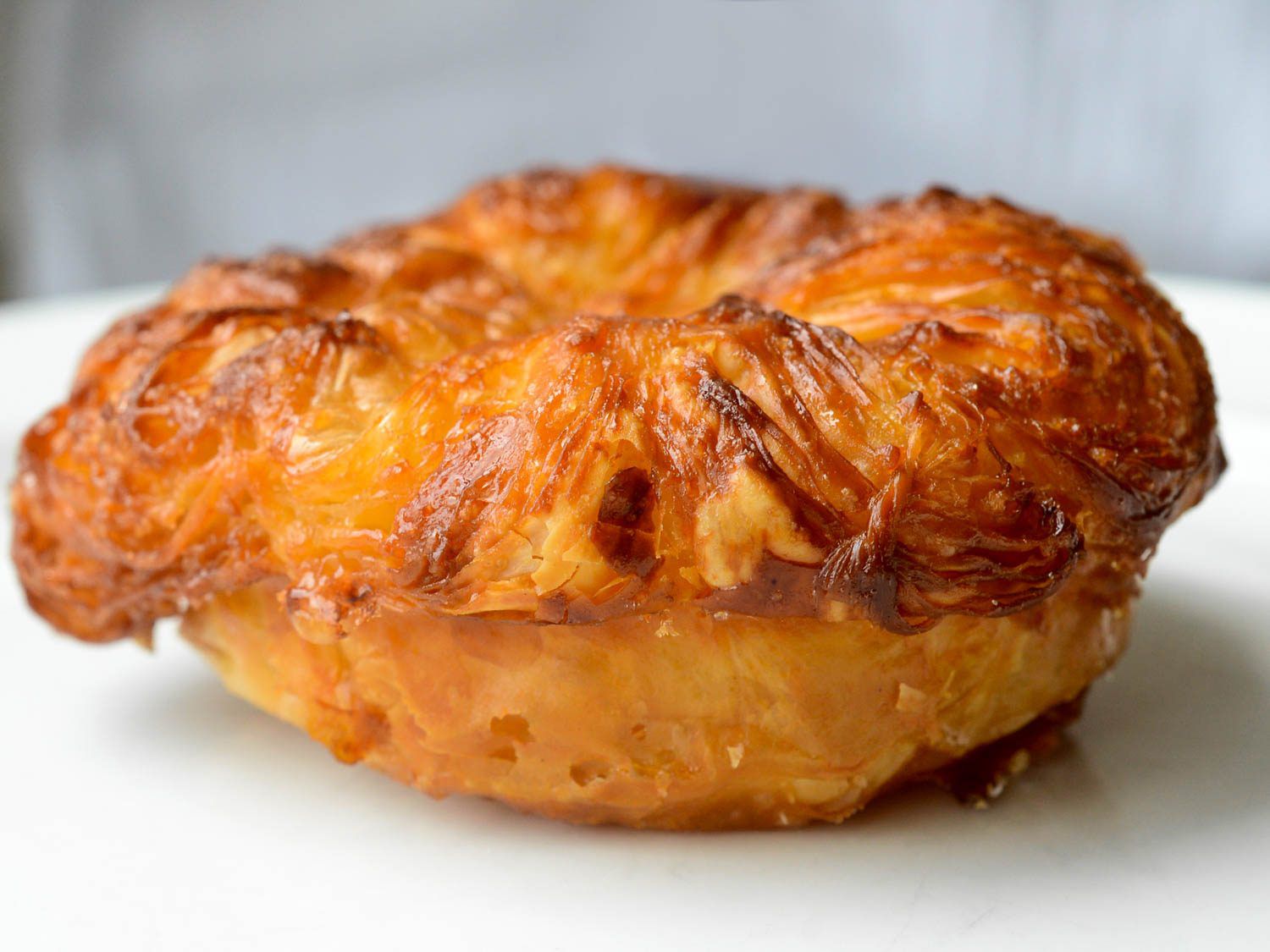 Side view of Kouign amann pastry on white serving plate.