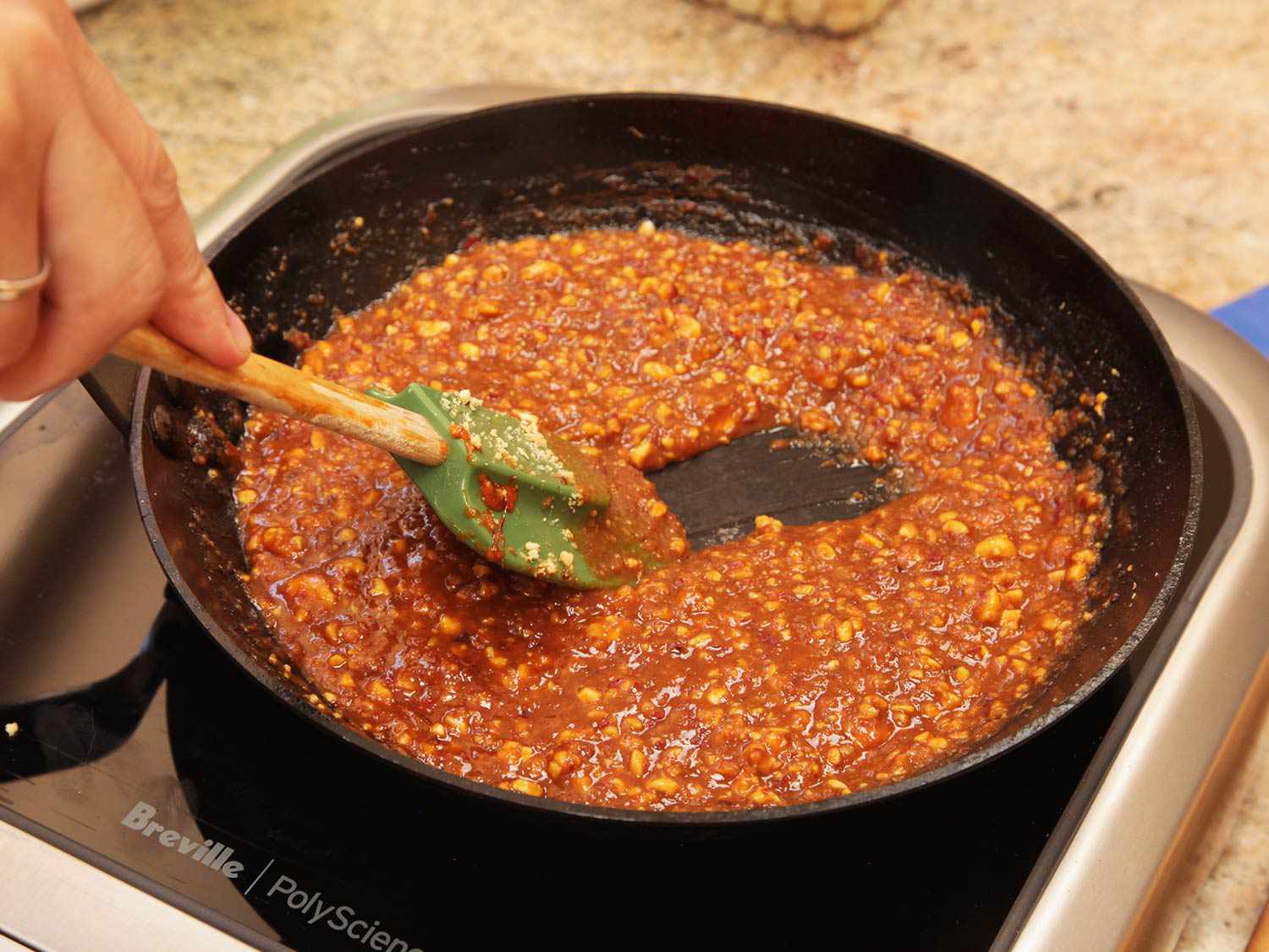 Stirring peanut sauce in a skillet to be served with pork satay.